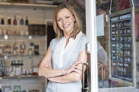 happy woman leaning on door of small business
